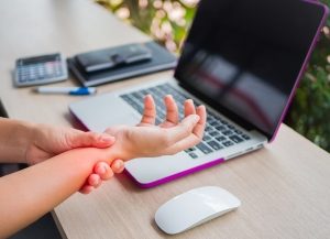 woman holding her wrist pain from using computer