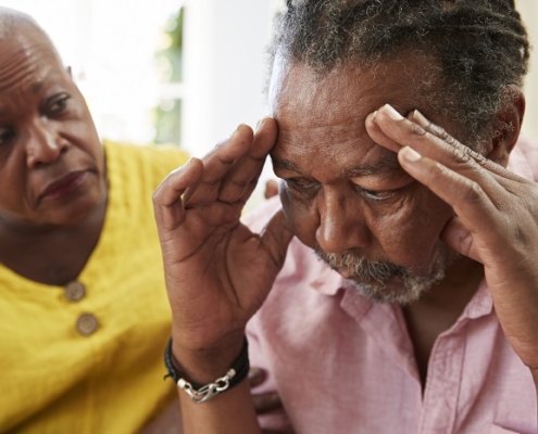 A man suffering from Alzheimer's disease is being comforted by a women.