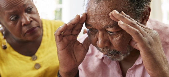 A man suffering from Alzheimer's disease is being comforted by a women.